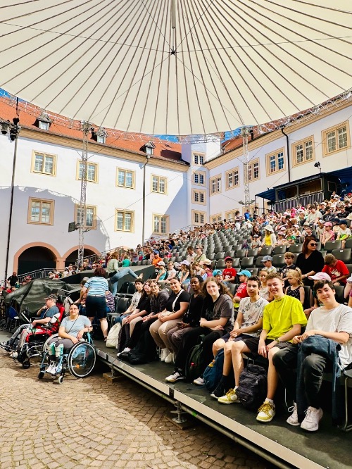Die Schüler.innen der Augustenburg Gemeinschaftsschule Grötzingen sitzen mit weiteren Zuschauern auf einer Tribüne.